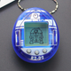 A close-up of the new blue and white R2-D2 branded Tamagotchi with the droid in pixels on its screen..
